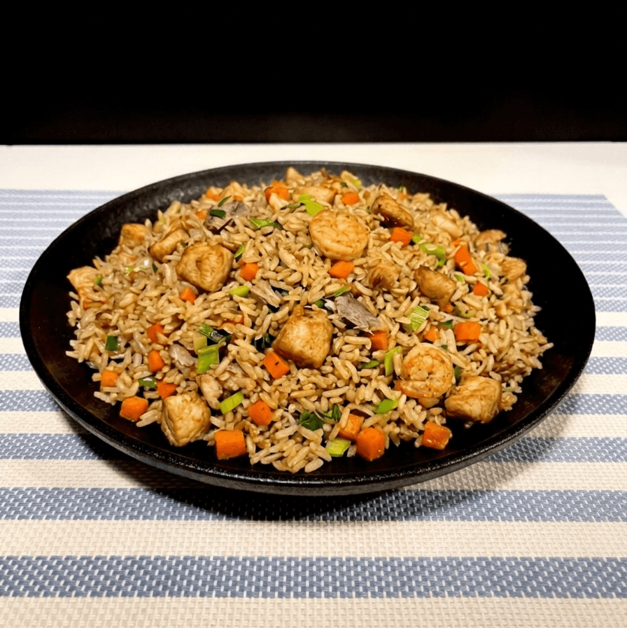 Fried rice with vegetables and mixed toppings on a black plate